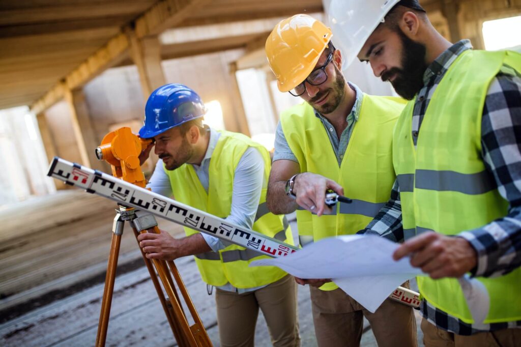 A group of construction workers on a job site wearing hardhats and yellow vests.