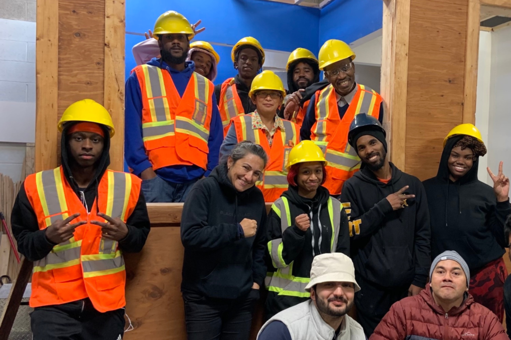 A group of construction students wearing reflective vests and smiling