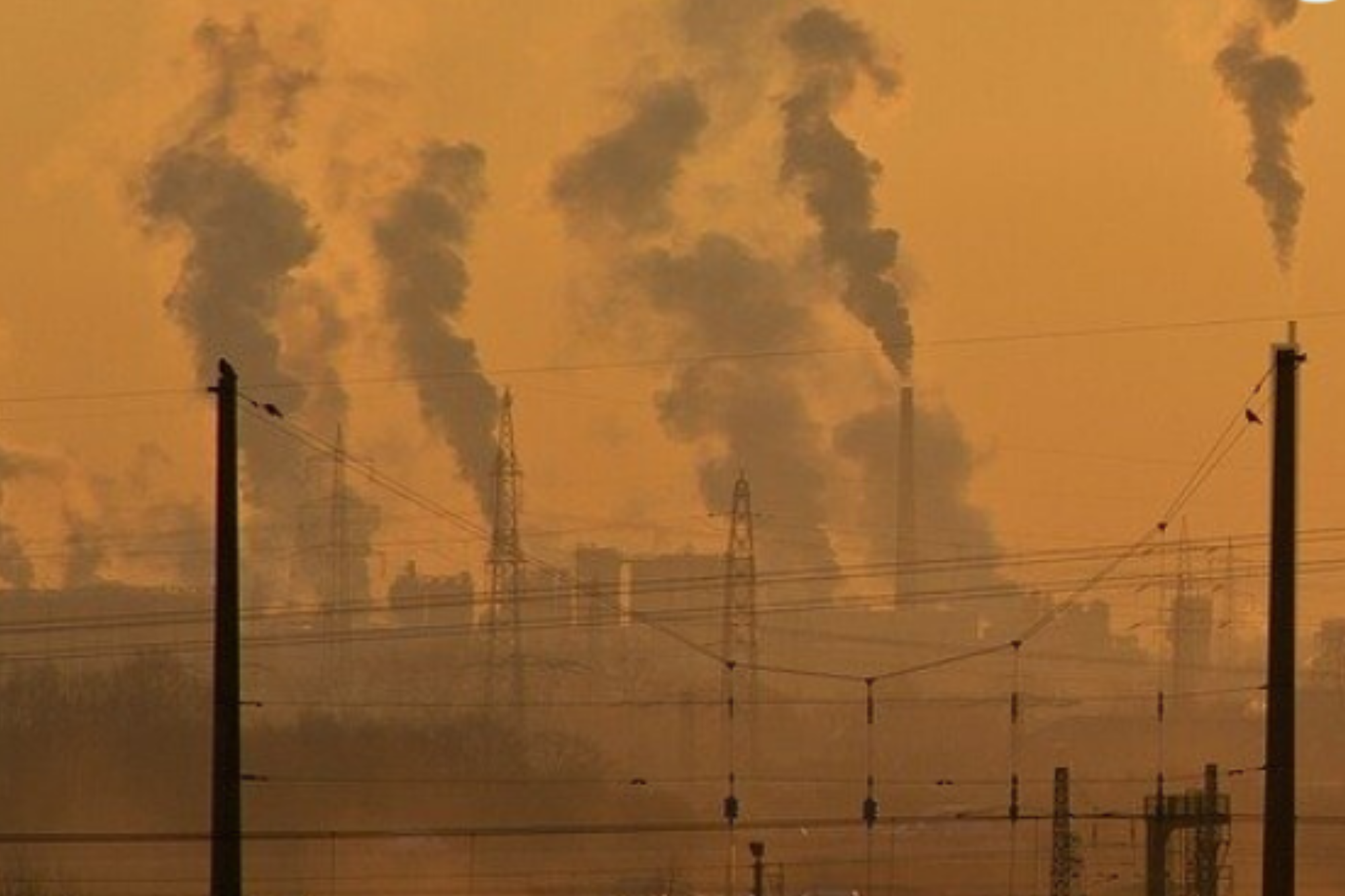 Smoke being blown into the air against a sunset backdrop.