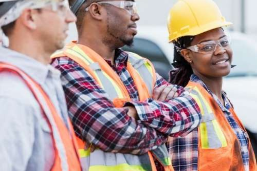 Group of 3 construction workers with one women smiling.