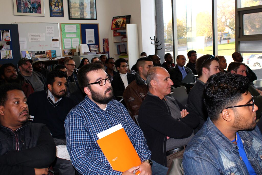 A group of people listens to discussions at the LEC job fair.