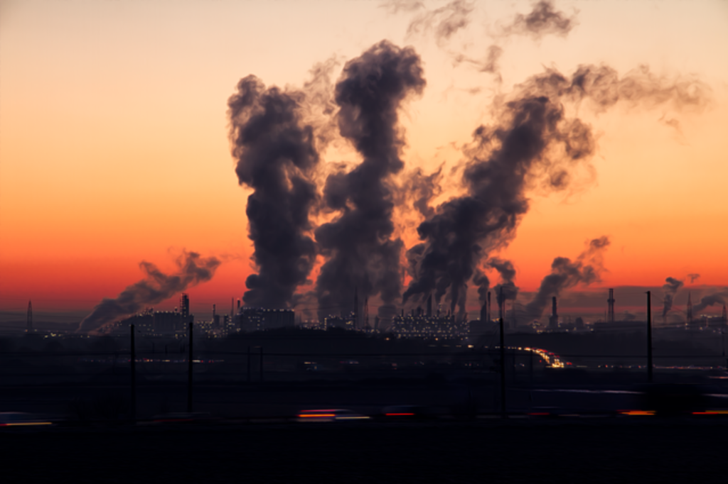 Smoke being blown into the air against a sunset.