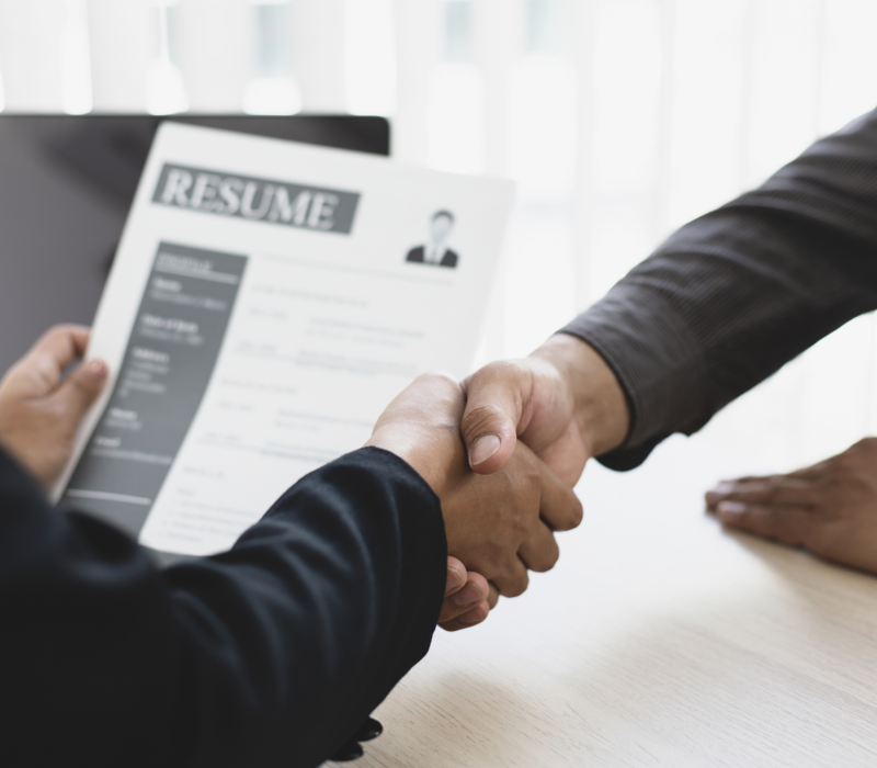 Two people shaking hands during a job interview.