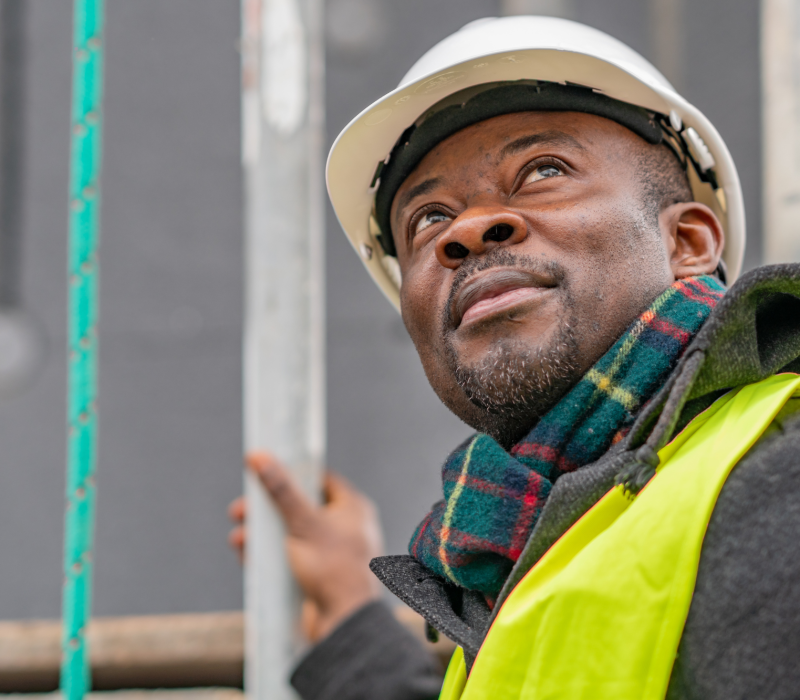 Black construction worker in a hardhat looking up to the sky