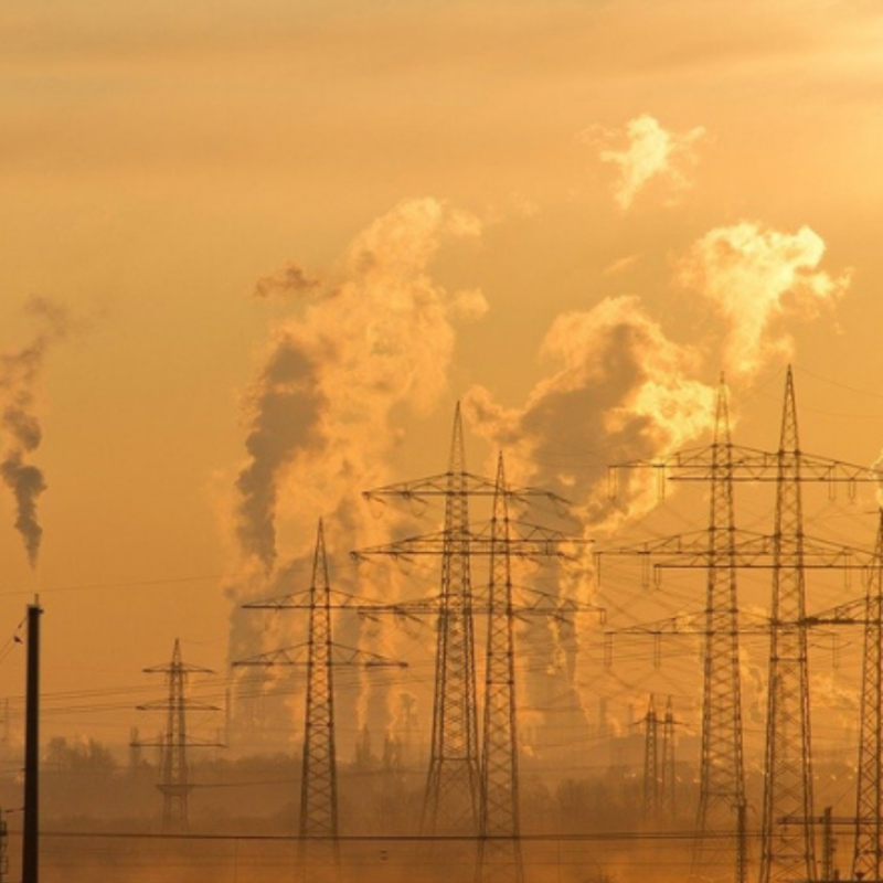 A photo of electrical towers against an orange sky with smoke rising in the background