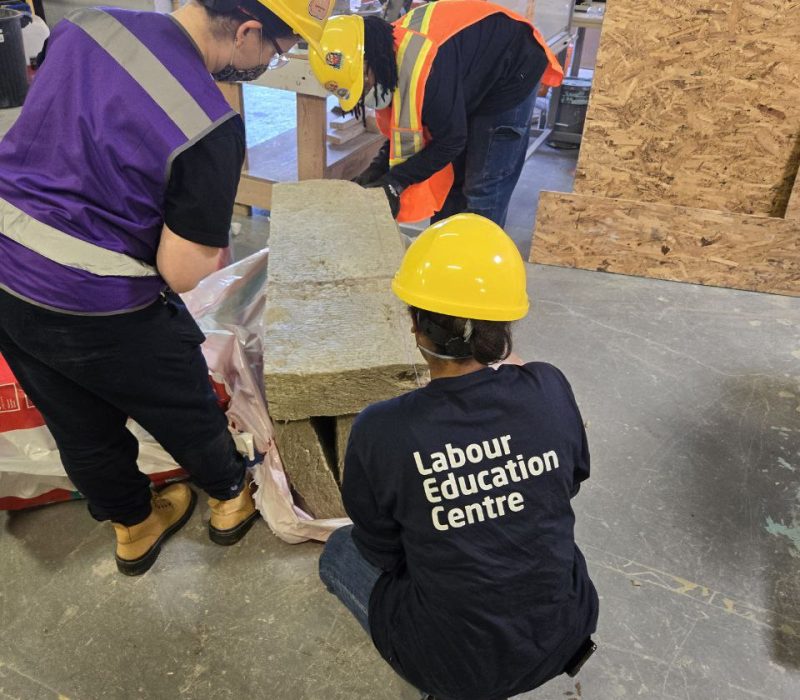 Construction students working while wearing Labour Education Centre shirts.